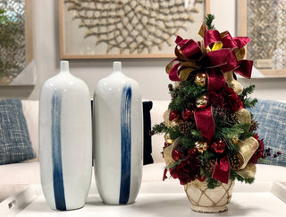 Burgundy hydrangea and berry decorated evergreen tree in ceramic pot