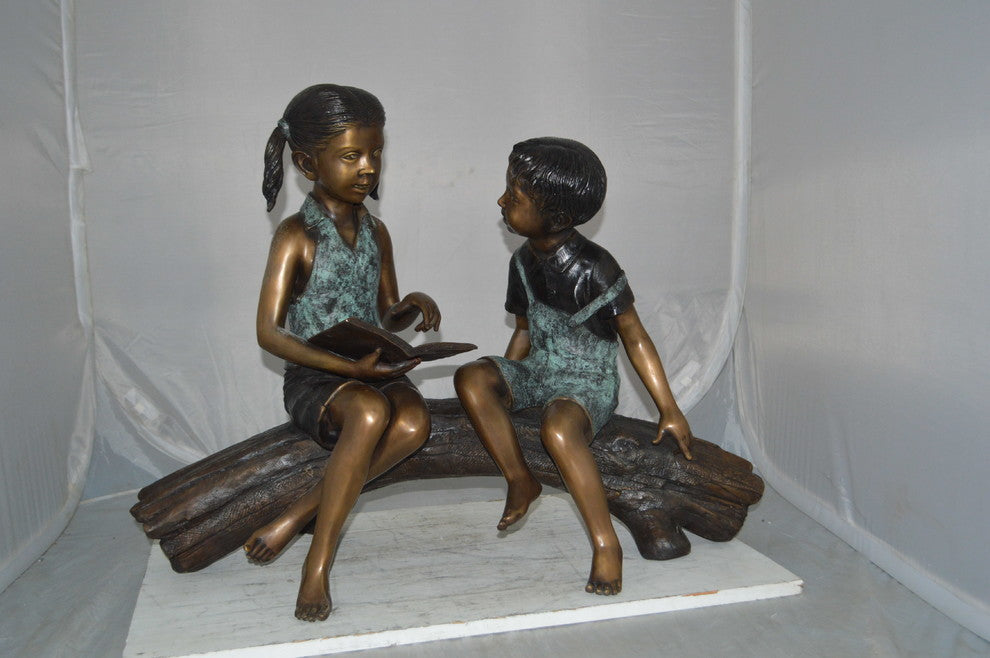 Boy and Girl on a tree log reading Bronze Statue -  Size: 37"L x 14"W x 27"H.