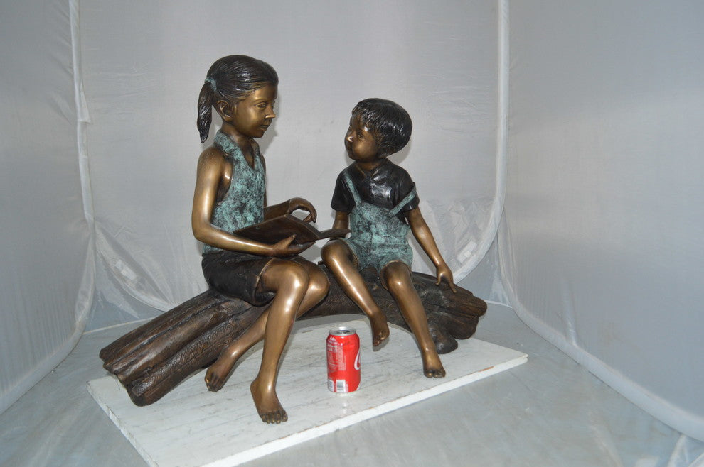 Boy and Girl on a tree log reading Bronze Statue -  Size: 37"L x 14"W x 27"H.
