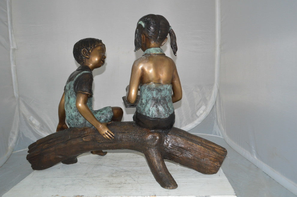 Boy and Girl on a tree log reading Bronze Statue -  Size: 37"L x 14"W x 27"H.