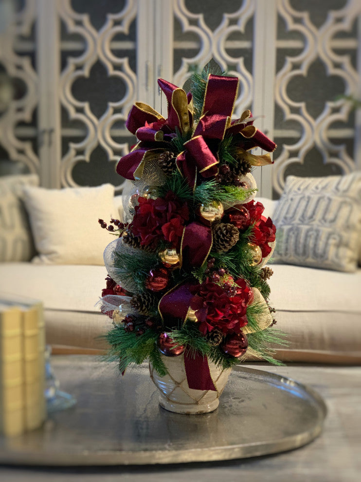Burgundy hydrangea and berry decorated evergreen tree in ceramic pot