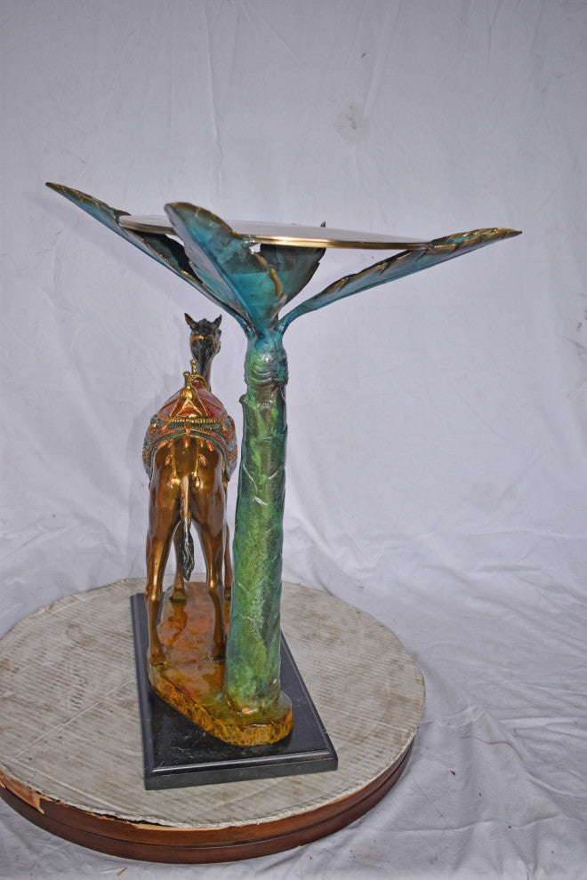 Camel Standing Under A Palm Tree Bronze Statue - Size: 20"L x 29"W x 25"H.