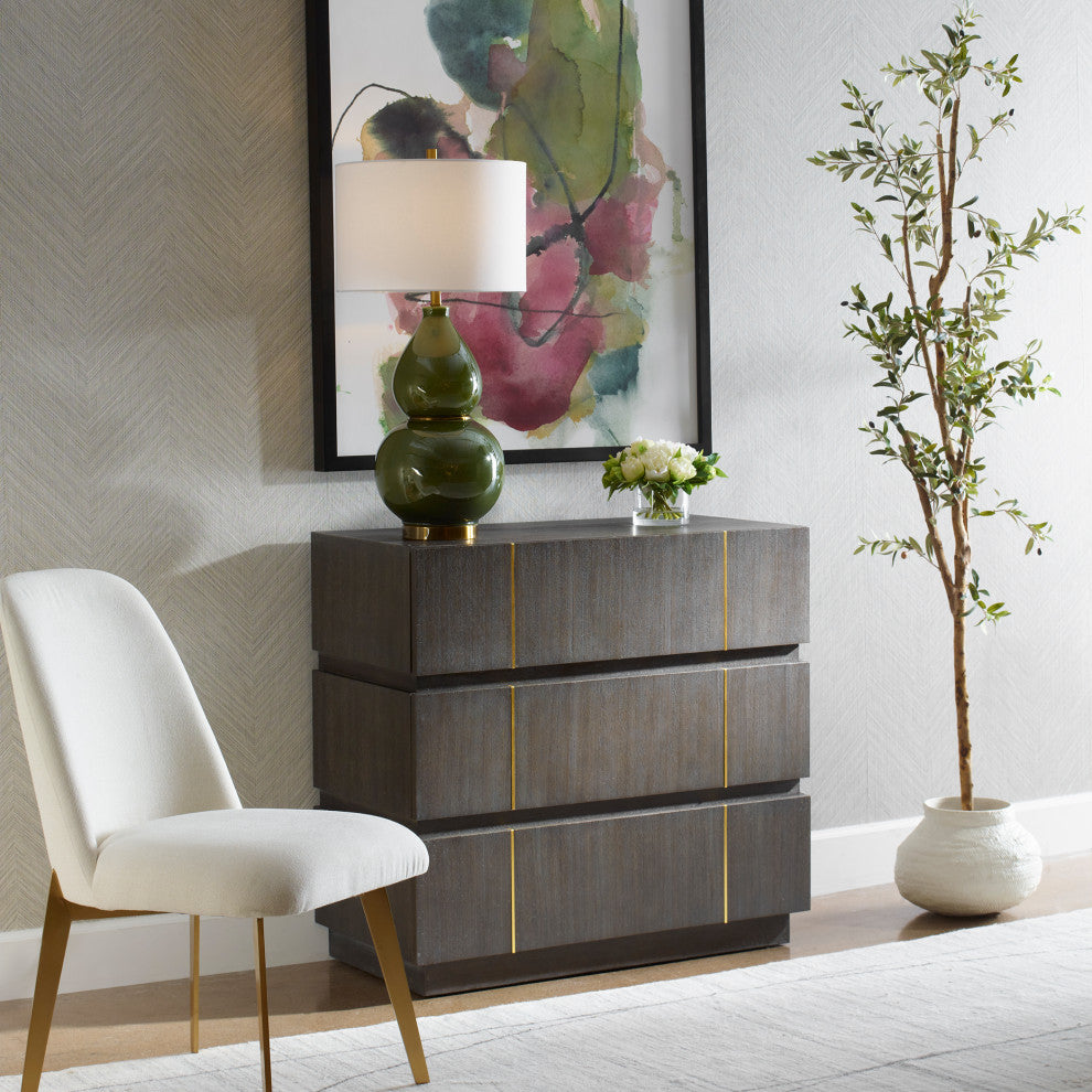 Lifestyle image: chest placed in a living space with chair and artwork.