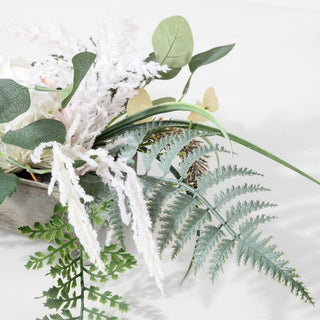 Close-up of textured leaves and frosted stems on white background.