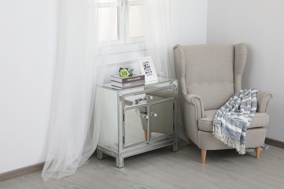 Lifestyle shot in a real room; cabinet is shown in context with chair and window.