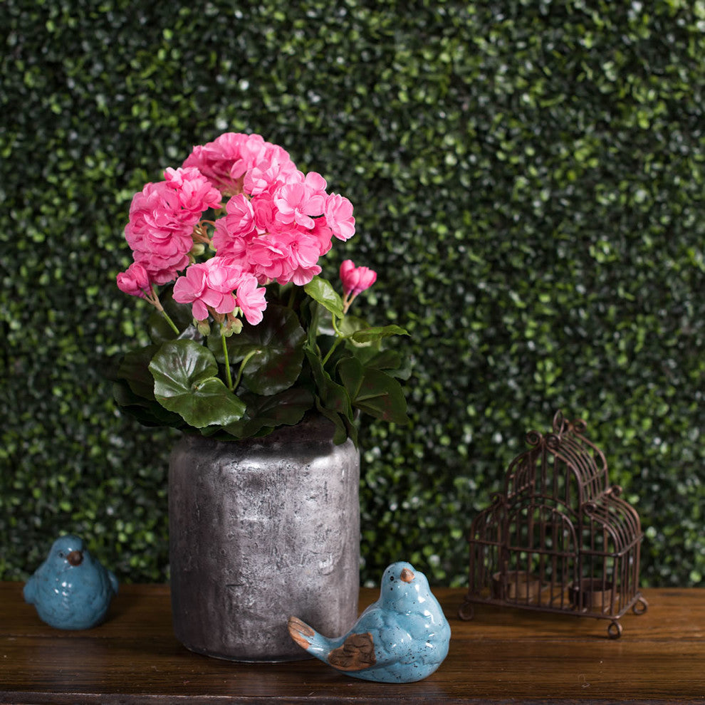Lifestyle shot: similar real-environment presentation of the geranium in a pot on a wooden surface with decor.