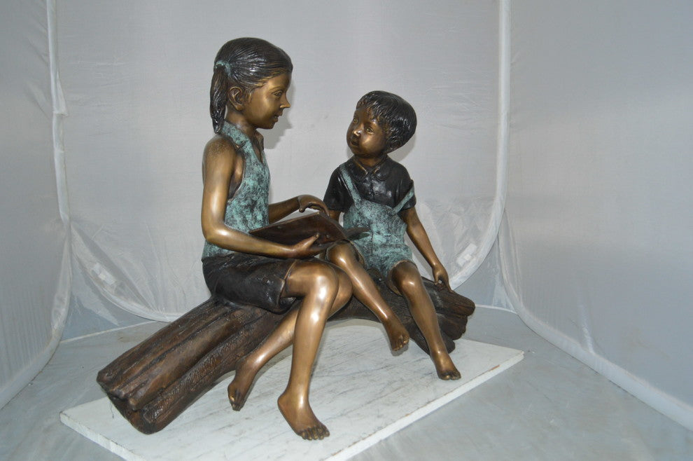 Boy and Girl on a tree log reading Bronze Statue -  Size: 37"L x 14"W x 27"H.